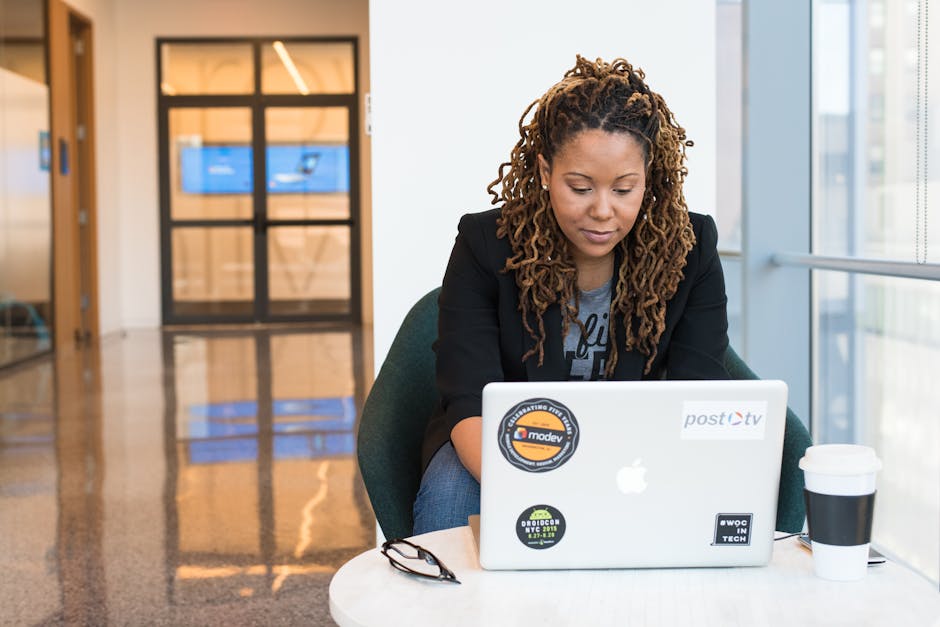A woman focused on her laptop in a modern office environment, signifying tech and business connection.
